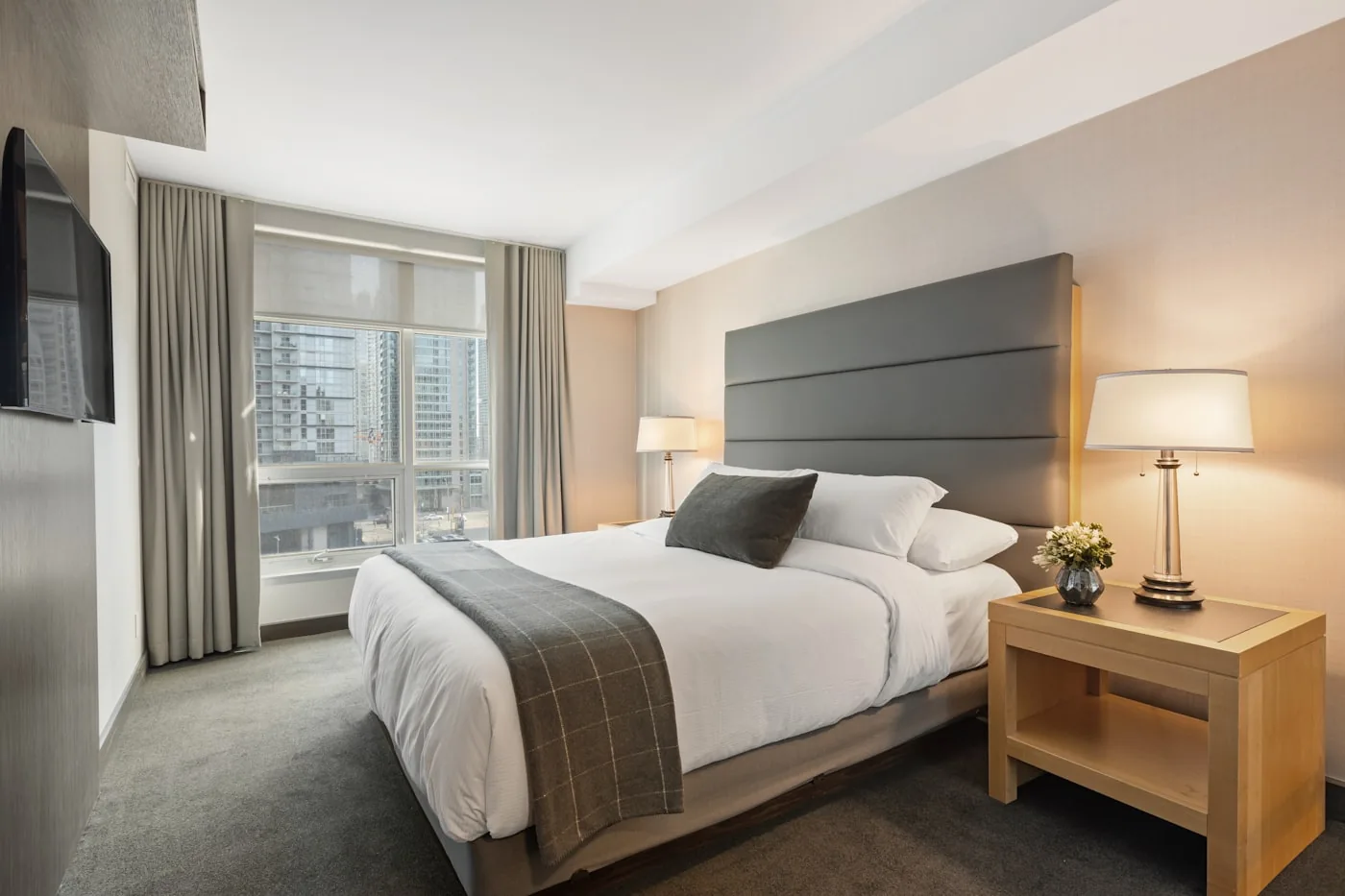 Made-up bedroom with white linen and a city view
